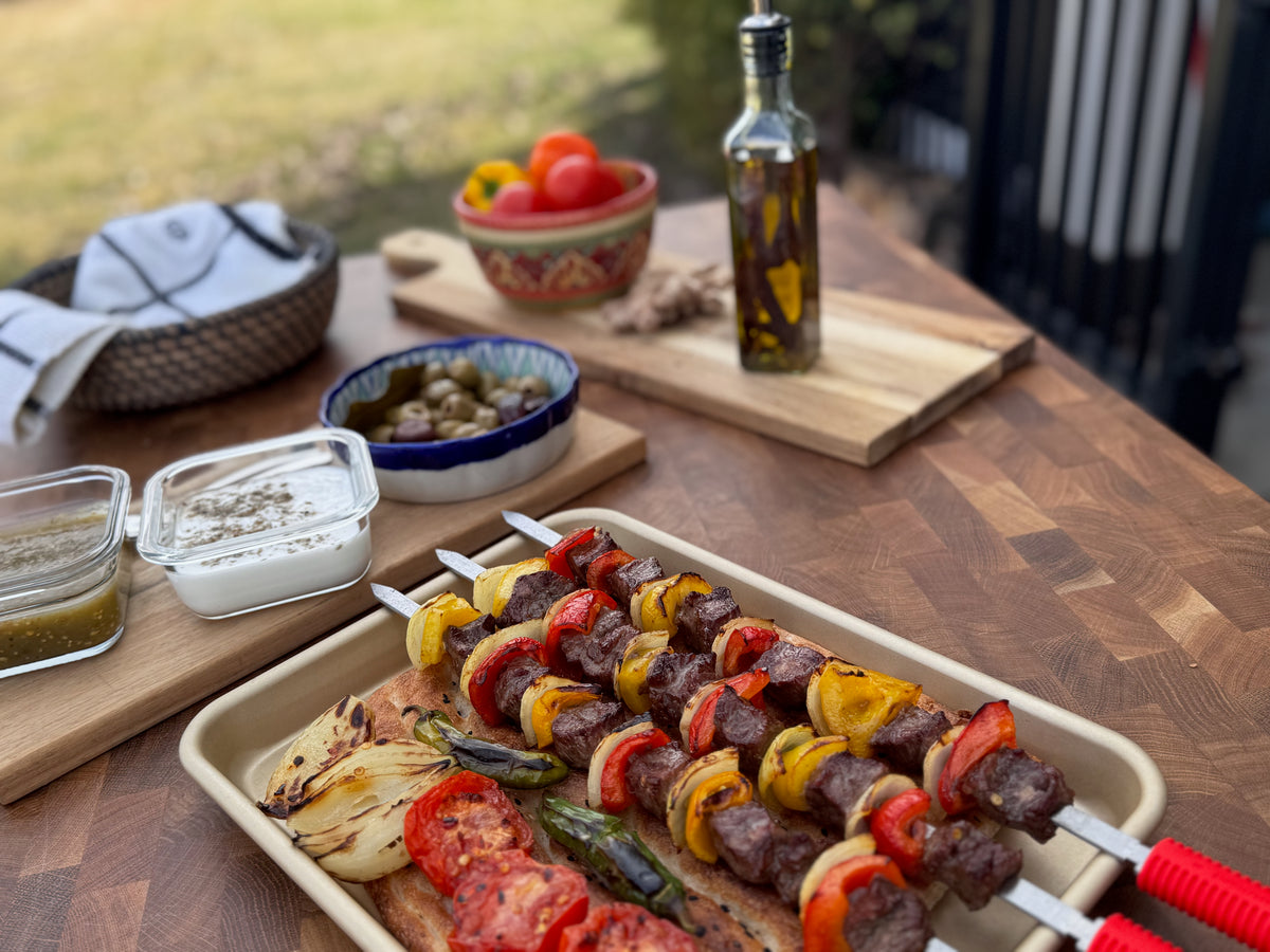 Grilled meat and pepper skewers with vegetables and bread on an outdoor table