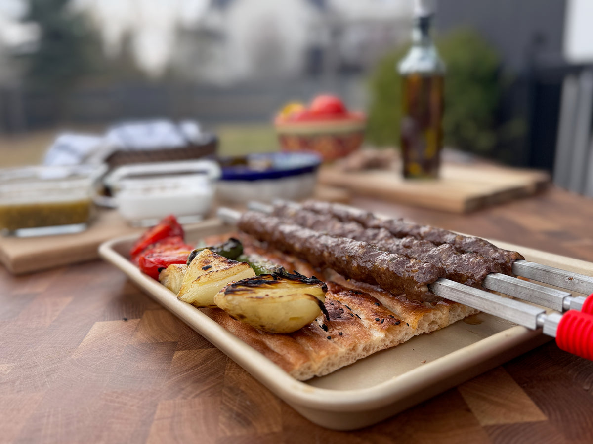 Seekh kabobs on square skewers, served over bread with grilled onions and red peppers