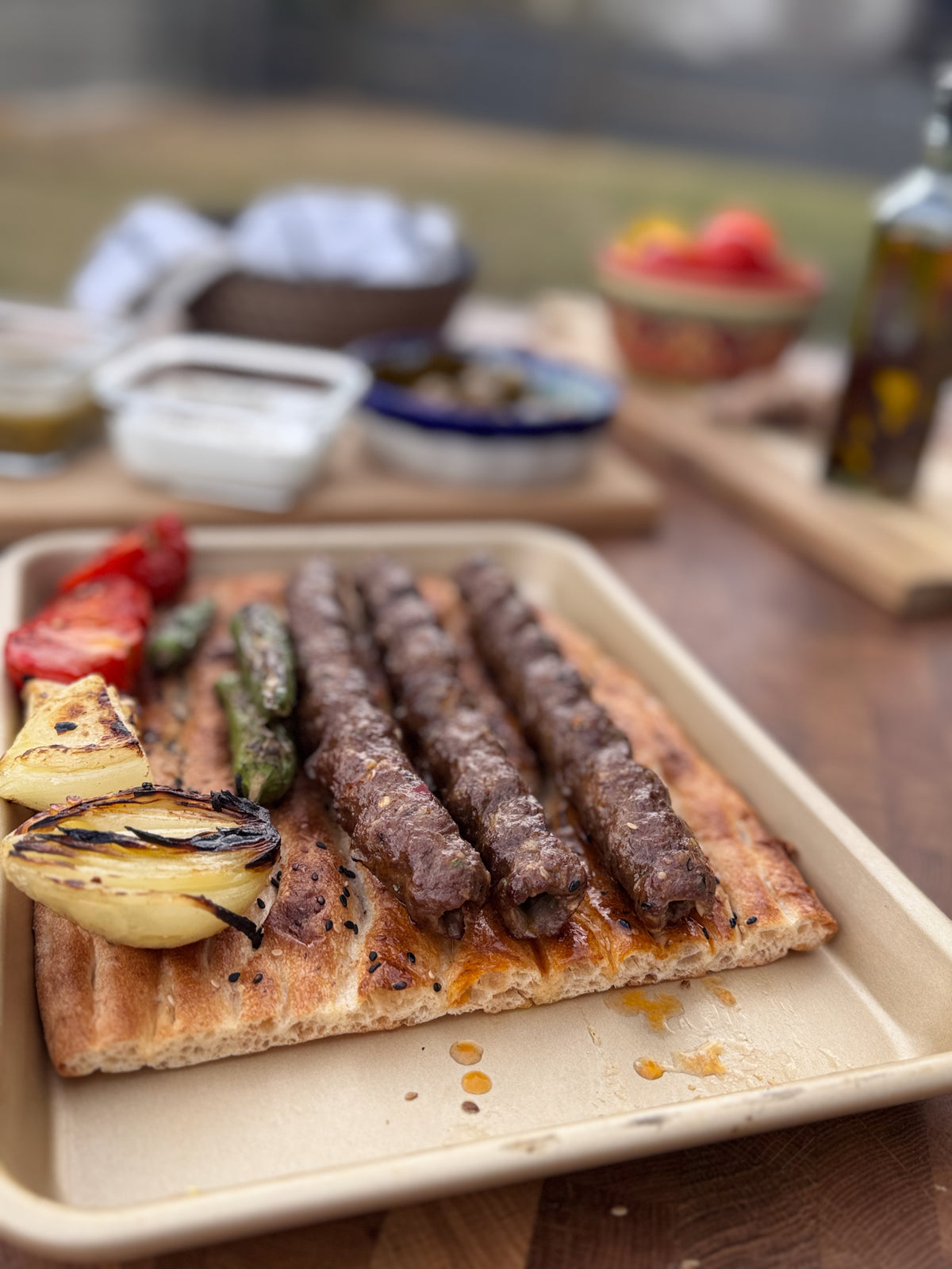 A platter of charcoal-grilled seekh kabobs with bread and grilled vegetables